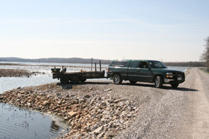 Photo of a pickup track with trailer backed up to a lake.
